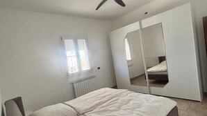A bedroom with a bed, a ceiling fan, a window, and a wardrobe. - Natura Pura Wellness Oasis near Laghetti di Cavagrande (Avola)