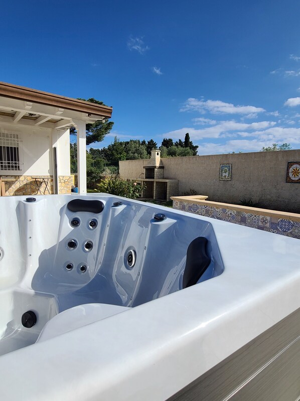 A hot tub with a stone wall and a tiled roof in the background. - Natura Pura Wellness Oasis near Laghetti di Cavagrande (Avola)