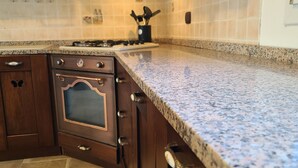 A kitchen with dark wooden cabinets, a stainless steel oven, and a granite countertop. - Natura Pura Wellness Oasis near Laghetti di Cavagrande (Avola)