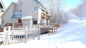 A two-story building with a green roof, wooden balconies, and a white fence. - Experience slope side on Salamander at The Haven! (Canaan Valley)