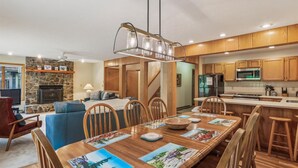 A modern kitchen with wooden cabinets, a central island, and a dining area with a long table and chairs. - Experience slope side on Salamander at The Haven! (Canaan Valley)