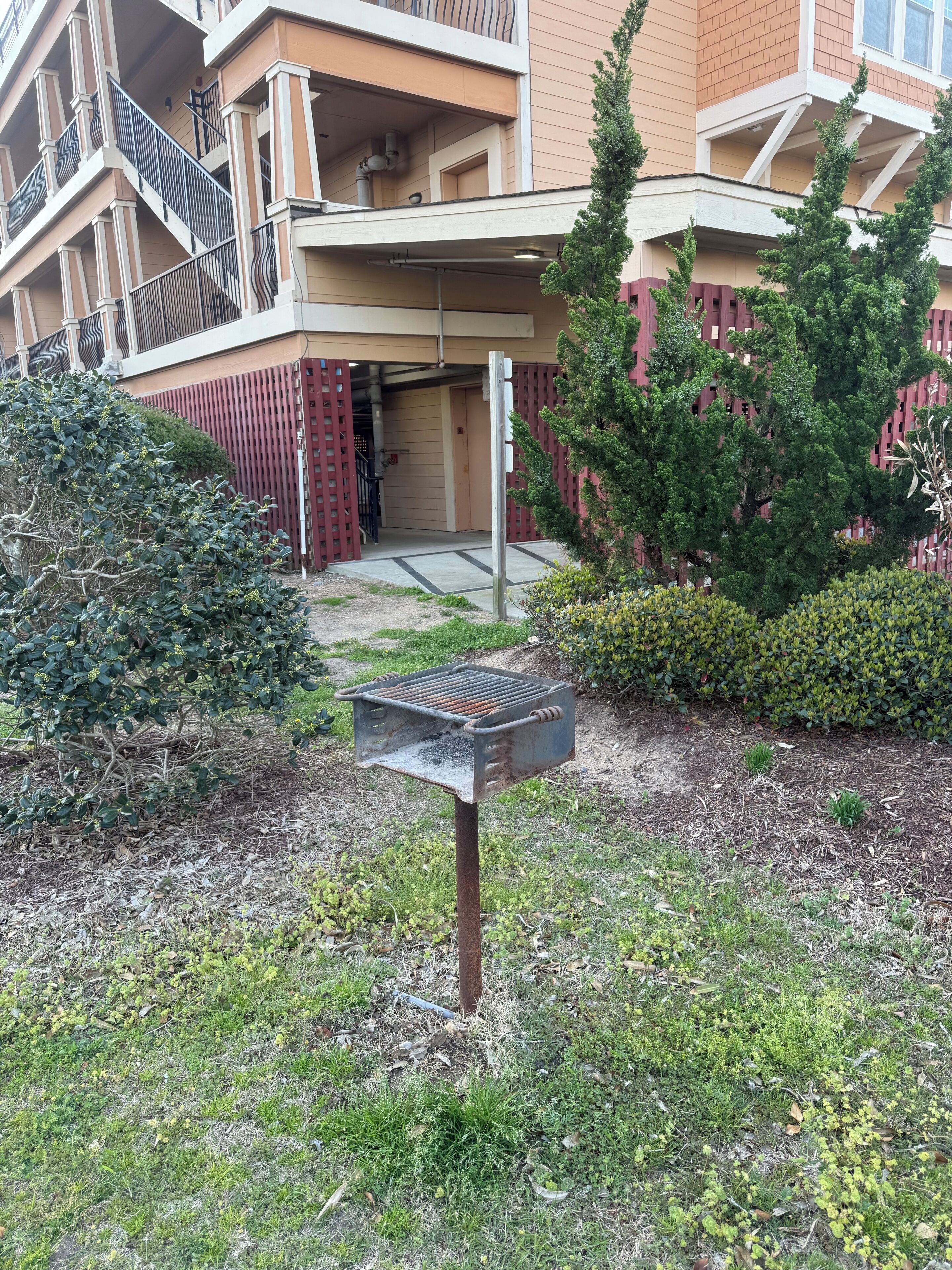 Een gebouw met een overdekte ingang, een metalen hekwerk en een rode afrastering.