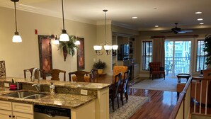 A spacious kitchen with granite countertops, a dishwasher, and a dining area with a large island and chairs. - Beachside Breeze - Pools, hot tub, & private beach access (Kill Devil Hills)