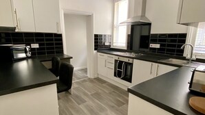 A modern kitchen with white cabinets, black countertops, and a grey herringbone floor. - Spacious Two Bed Apartment in Poole (Poole)