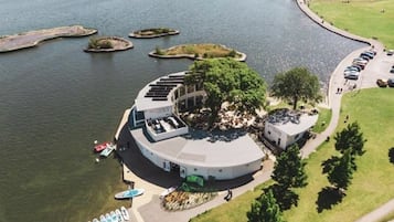An aerial view of a circular building with a central courtyard, surrounded by water and small islands.