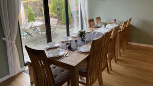 A dining area with a table set for six, large windows, and a view of the garden. - Dream house on the Maar (Schalkenmehren)