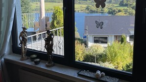 A window with a view of a lake, a statue, and a butterfly decoration. - Dream house on the Maar (Schalkenmehren)