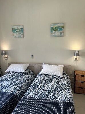 A double bed with patterned bedding, two bedside lamps, and two paintings on the wall. - Immaculate Two Beds Luxury Marina Apartment (Black River)