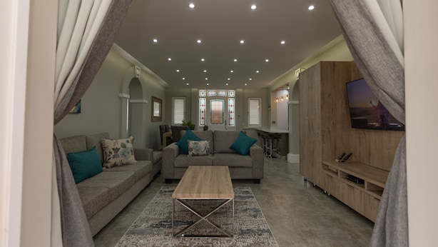 A modern living room with a sofa, coffee table, and TV stand. - Caribbean Estates - 35 Montego Bay (Port Edward)