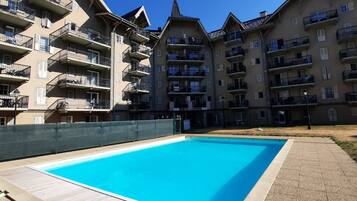 Une piscine entourée d’immeubles résidentiels à plusieurs étages, dotés de balcons.