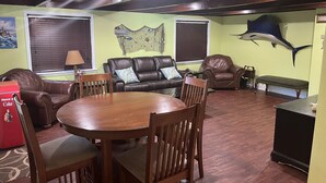 Ein geräumiges Wohnzimmer mit einem Holzessttisch, Ledersofas und einem an der Wand befestigten Fisch.