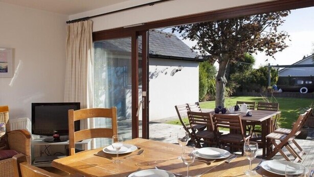 A dining area with a table set for four, a television, and a view of the garden.