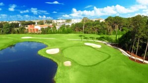 A golf course with a pond, sand bunkers, and surrounding trees. - Pelican Isle 217 Gulf front with Balcony sleeps 6 (Fort Walton Beach)