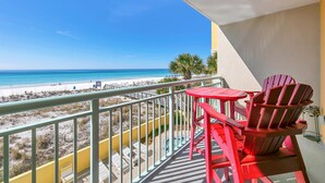 A balcony with red Adirondack chairs and a view of the beach. - Pelican Isle 217 Gulf front with Balcony sleeps 6 (Fort Walton Beach)