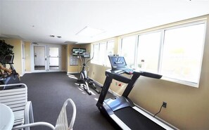 A fitness room with treadmills, stationary bikes, and a white chair.
