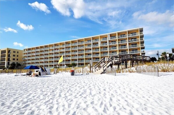 Ein mehrstöckiges Hotel mit Balkonen direkt am Sandstrand.