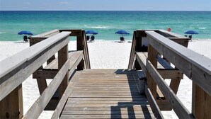 A wooden boardwalk leading to a beach with blue umbrellas and chairs. - Pelican Isle 217 Gulf front with Balcony sleeps 6 (Fort Walton Beach)