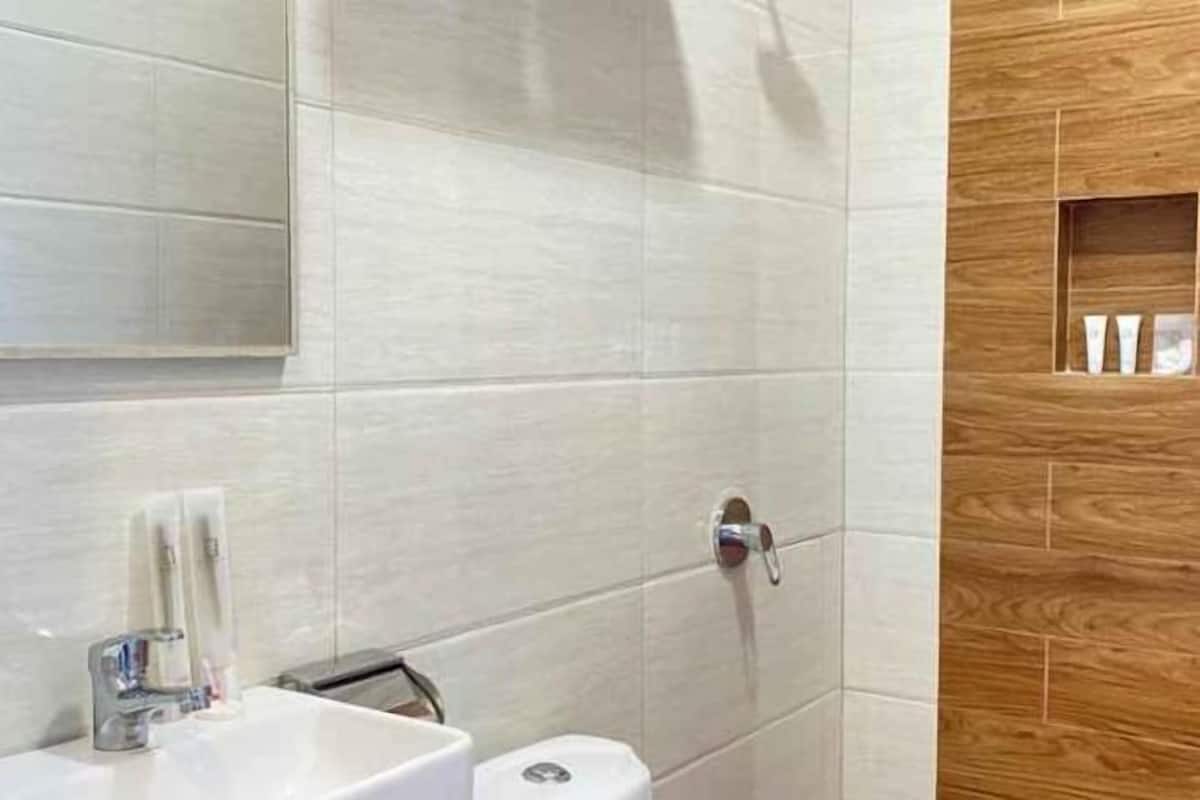 Bañera con ducha, pantuflas, toallas