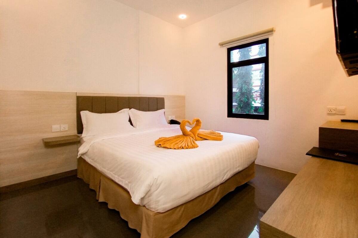 Een hotelkamer met een bed, nachtkastje, bureau en raam.