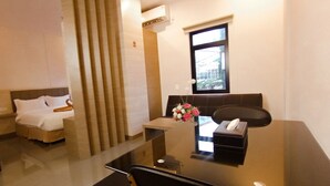 A hotel room with a bed, a desk with a computer, a chair, and a window. - Batam 1 Hotel (Batam)