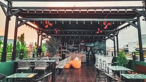 An outdoor cafe with a tiled floor, wicker chairs, and a bar area. - Batam 1 Hotel (Batam)