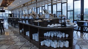 A modern restaurant with a central buffet area, large windows, and a polished tile floor. - Batam 1 Hotel (Batam)