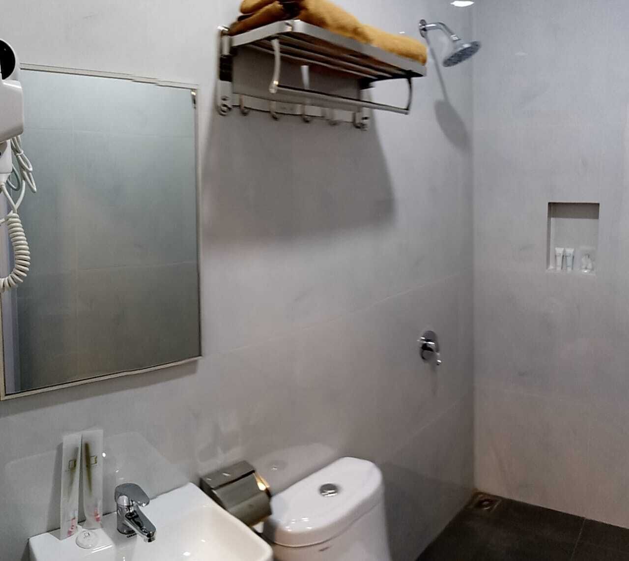 Une salle de bain comprenant des toilettes, un lavabo et un espace douche avec un porte-serviettes.