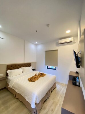 A hotel room with a bed, a TV, an air conditioner, and a small window. - Batam 1 Hotel (Batam)
