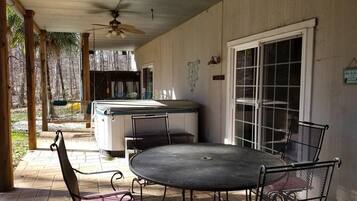 A covered patio with a round table and chairs, a ceiling fan, and a view of the surrounding area.