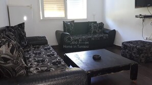 A living room with a sofa, a coffee table, and a patterned ottoman.