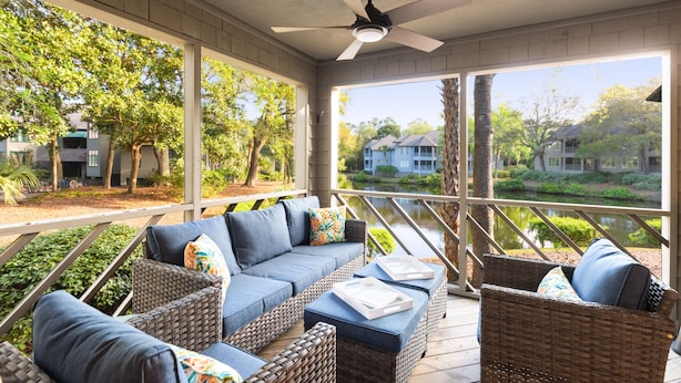 A covered outdoor seating area with wicker furniture and a ceiling fan.