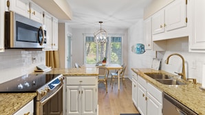 A modern kitchen with white cabinetry, stainless steel appliances, and a granite countertop.
