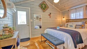 Een gezellige slaapkamer met een houten plafond, een bed met een blauw-witte dekbedovertrek, een bankje, een spiegel en een deur met een krans.