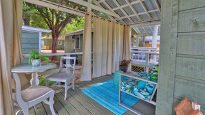 A covered patio area with a table and chairs, a small seating area with cushions, and a view of the surrounding property.