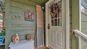 A green wooden door with a 'Welcome' sign, a birdhouse, and a wreath.