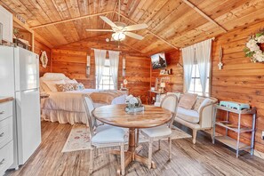 A cozy cabin with a wooden interior, a round dining table, and a bed with a canopy.