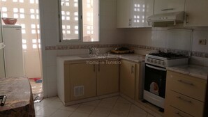 Una cocina con gabinetes blancos, estufa y ventana con vista a edificios.