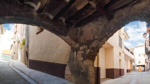 Un pas subterràni amb arcs de pedra, un carrer estret i edificis amb balcons i finestres.