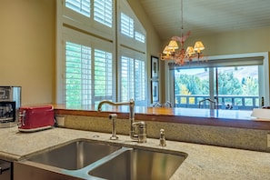 A kitchen with a double sink, a red toaster, and a view of a balcony with a railing. - Wildflower Condo 671 - Beautiful Sun Valley Resort Condo For 8 Guests (Sun Valley)