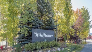 A sign with the name 'Wildflower' surrounded by trees and greenery.