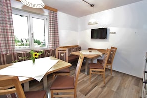 A dining area with a wooden table, chairs, and a television mounted on the wall. - Apartment in Sankt Johann near Ski Area (Sankt Johann im Pongau)