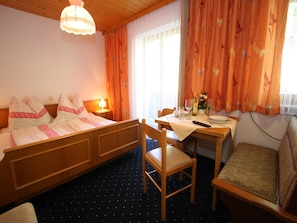 Habitación de hotel con cama, escritorio con silla, mesa con silla y ventana con cortinas.