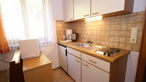 A compact kitchen with a sink, stove, and coffee maker.