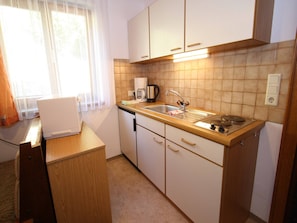 Cocina compacta con lavamanos, estufa y cafetera.
