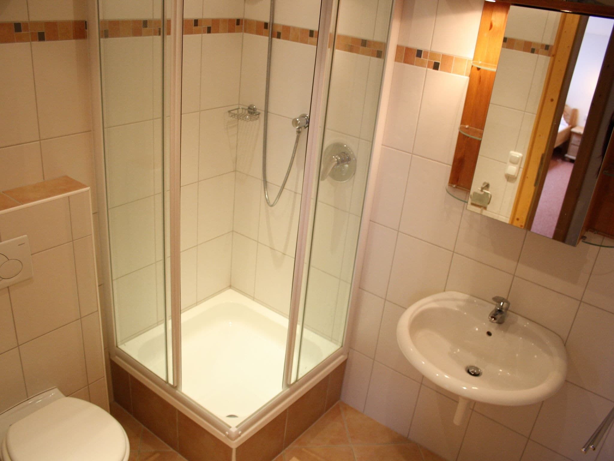 Un baño con cabina de ducha de vidrio, un lavabo blanco y un inodoro.
