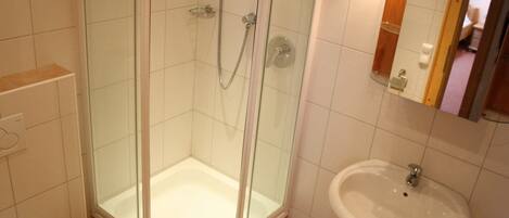 Un baño con cabina de ducha de vidrio, un lavabo blanco y un inodoro.