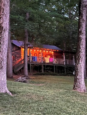 Une cabane en bois avec un porche, entourée d’arbres.