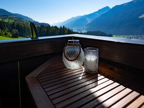 Une terrasse en bois agrémentée de deux photophores en verre, offrant une vue sur un paysage montagneux.
