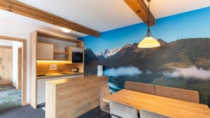 A modern kitchen with wooden cabinets, a built-in oven, and a large window overlooking a mountainous landscape. - Apartment in Wald near Zillertal Arena (Wald im Pinzgau)