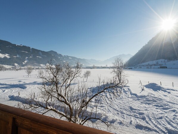 A snowy landscape with a clear sky and mountains in the background.